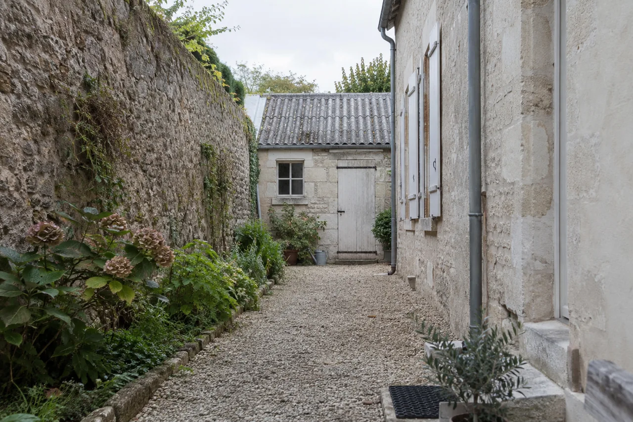 Passage étroit entre murs de pierre menant à une dépendance au fond d’une cour