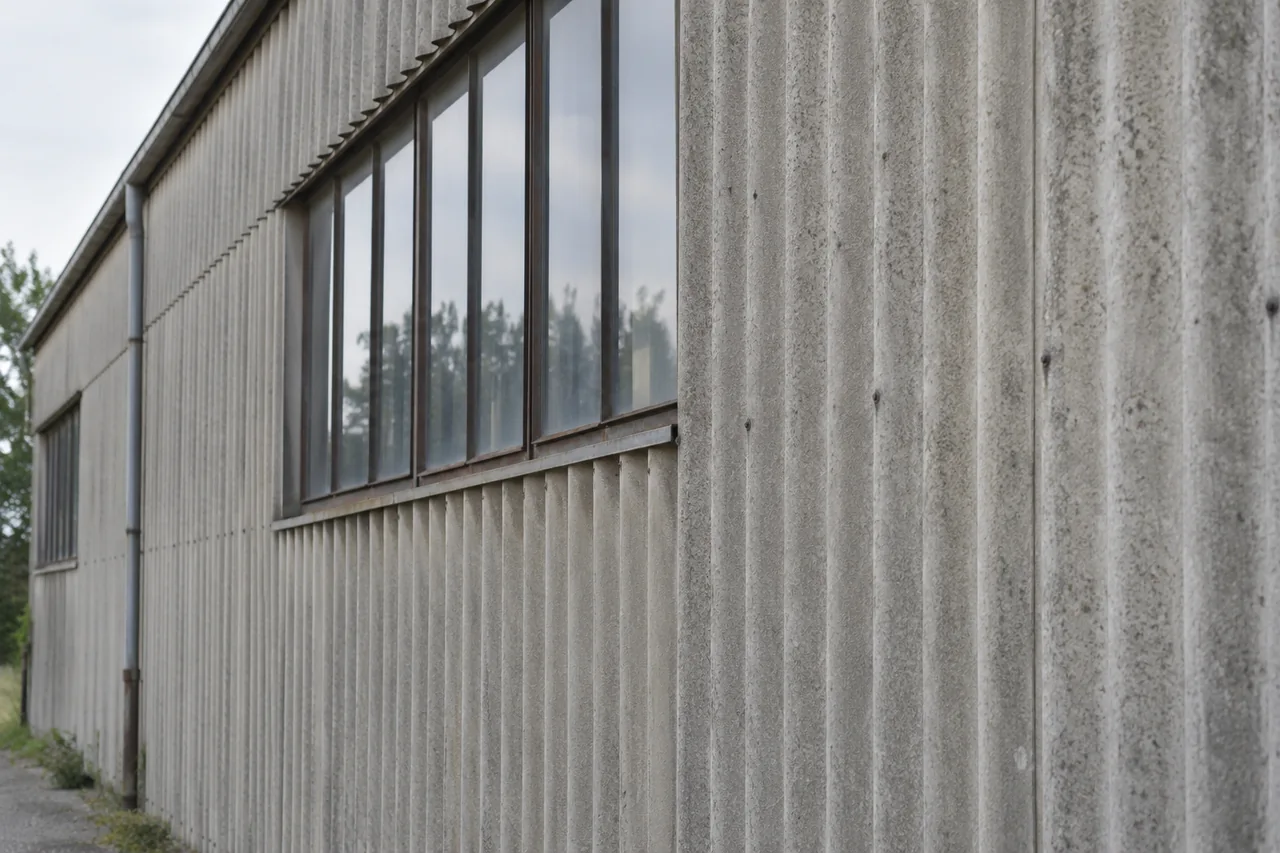Façade de bâtiment en plaques ondulées verticales grises autour d’une fenêtre